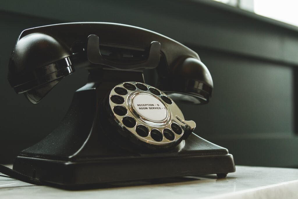 Teléfono antiguo de disco negro sobre mesa, símbolo de contacto